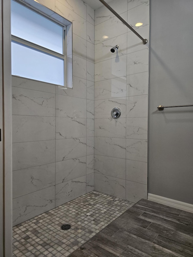 bathroom with hardwood / wood-style flooring and tiled shower