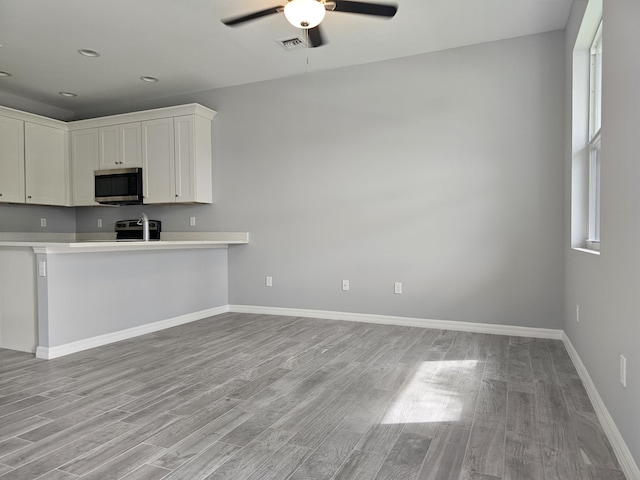 kitchen with light hardwood / wood-style flooring, ceiling fan, range, white cabinets, and kitchen peninsula