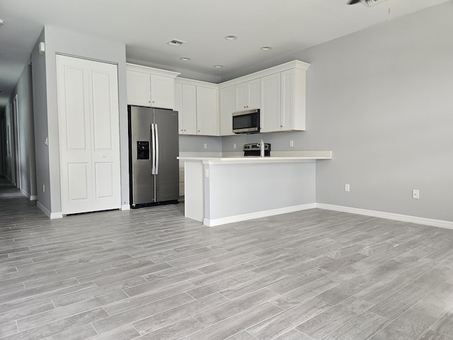 kitchen featuring stainless steel appliances, white cabinets, light wood-type flooring, and kitchen peninsula