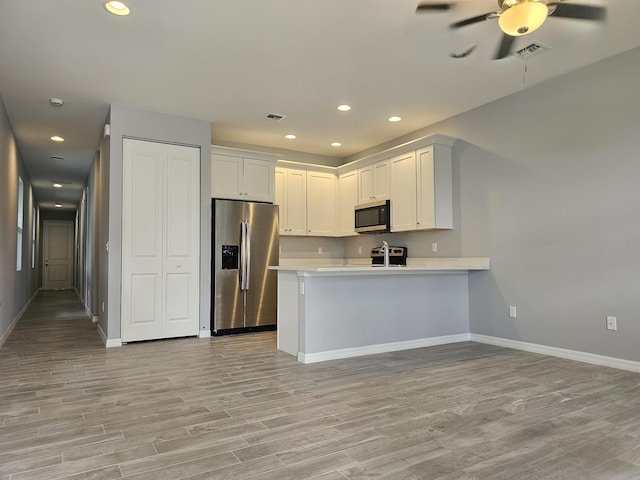 kitchen featuring appliances with stainless steel finishes, kitchen peninsula, white cabinetry, ceiling fan, and light hardwood / wood-style floors