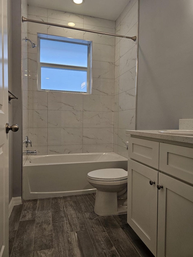 full bathroom featuring vanity, tiled shower / bath combo, and toilet