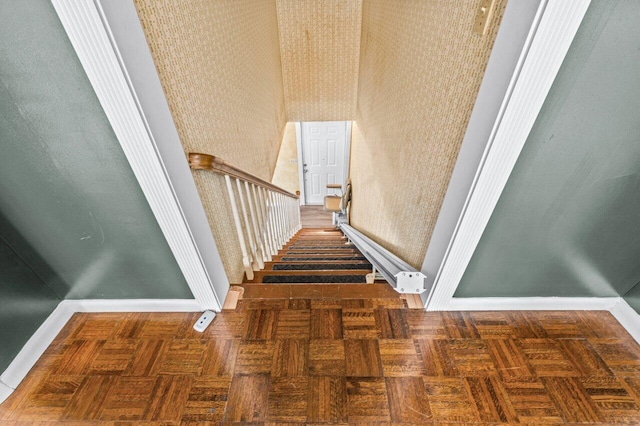 stairs with wallpapered walls and baseboards