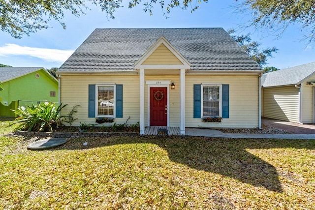 bungalow featuring a front lawn and roof with shingles