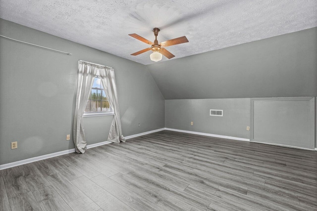 bonus room with a textured ceiling, wood finished floors, visible vents, and lofted ceiling