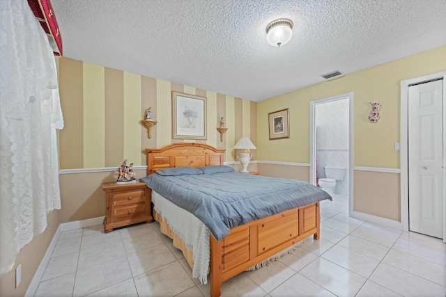 tiled bedroom featuring ensuite bathroom and a textured ceiling