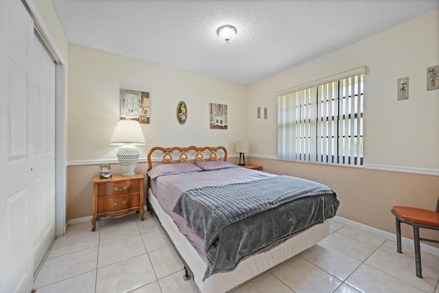 bedroom featuring light tile patterned flooring, a closet, and a textured ceiling