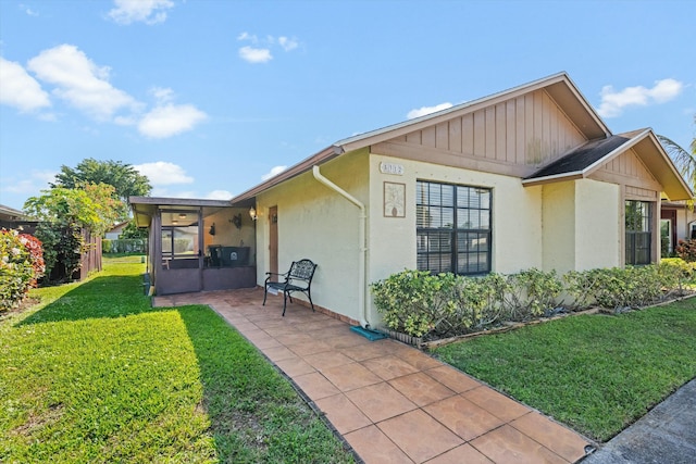 view of side of home featuring a sunroom, a patio area, and a lawn