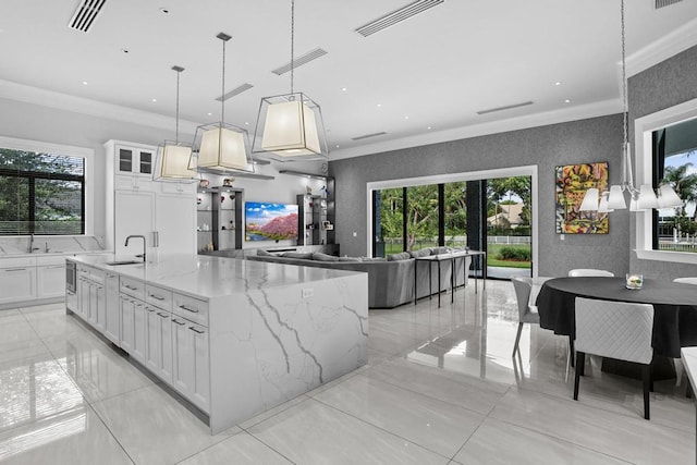 kitchen with crown molding, light stone counters, hanging light fixtures, a large island, and white cabinets