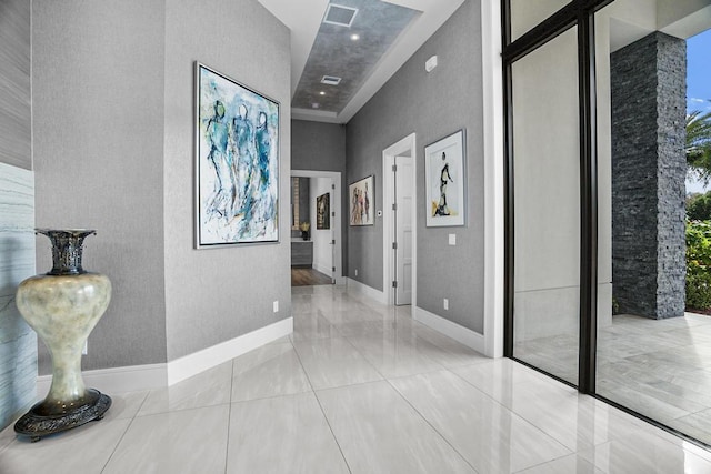 hallway featuring light tile patterned floors and a high ceiling