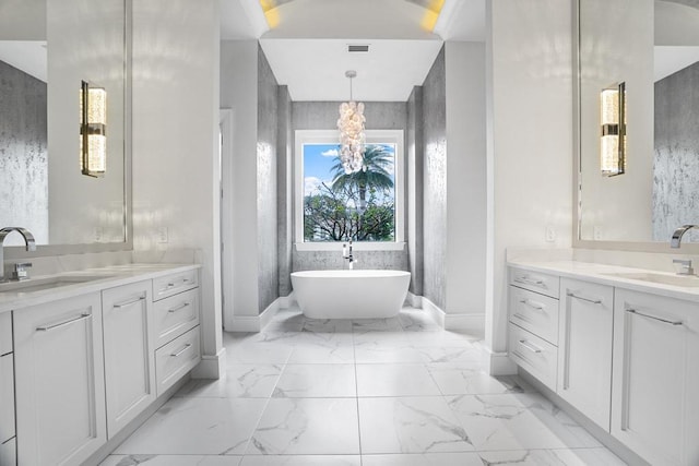 bathroom with an inviting chandelier, a tub to relax in, and vanity