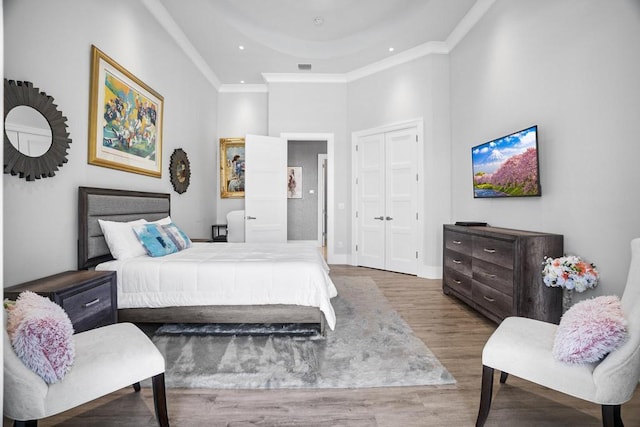 bedroom featuring crown molding, dark wood-type flooring, a towering ceiling, a raised ceiling, and a closet