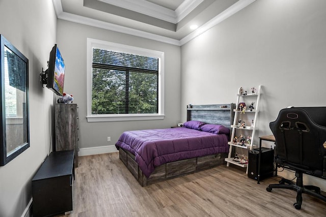 bedroom with a raised ceiling, wood-type flooring, and ornamental molding