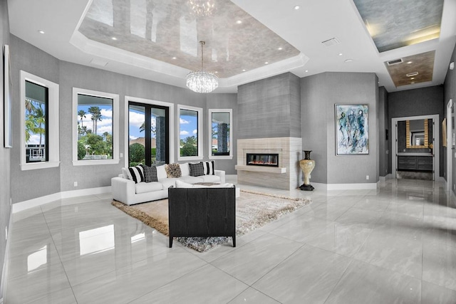 living room featuring a raised ceiling, a large fireplace, an inviting chandelier, and a towering ceiling