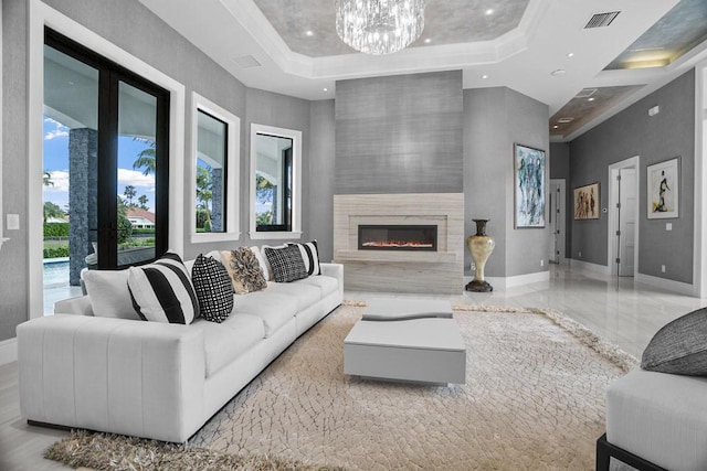 living room with an inviting chandelier, a towering ceiling, a fireplace, and a raised ceiling