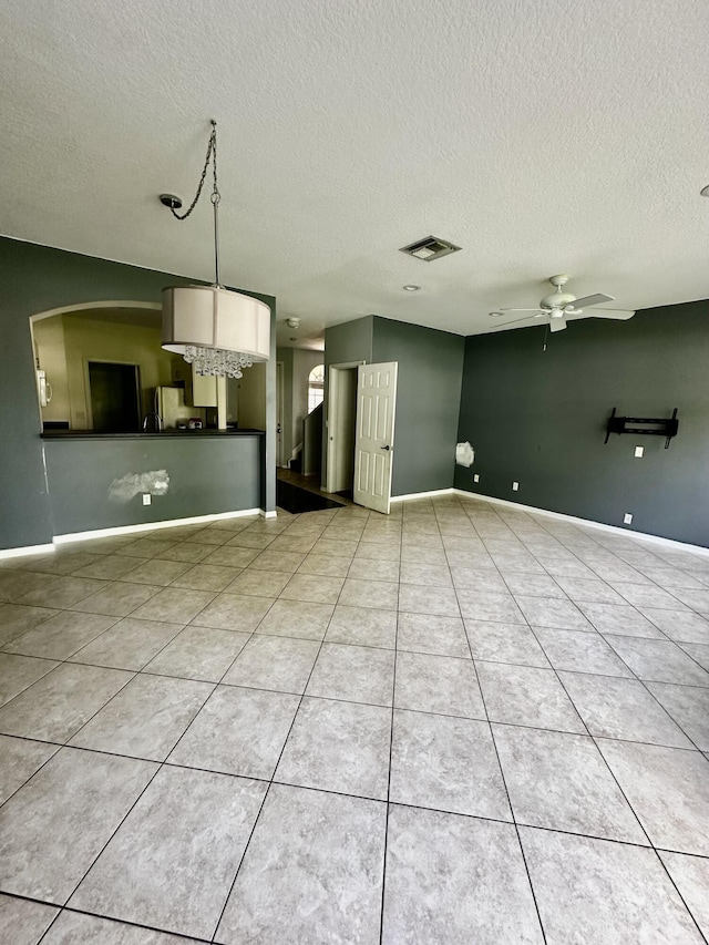 unfurnished living room featuring light tile patterned floors, a textured ceiling, and ceiling fan