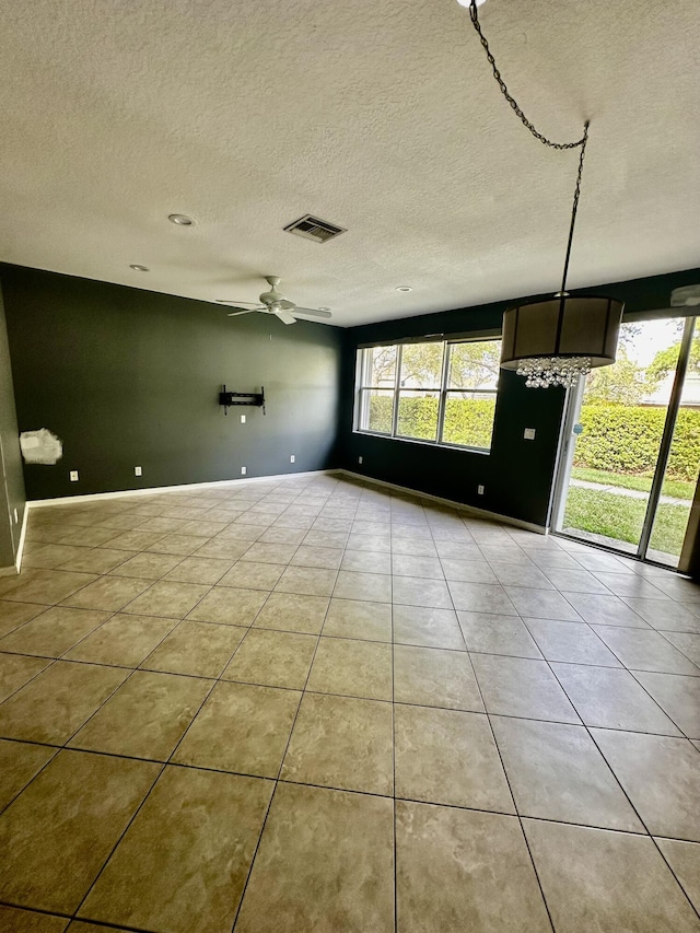 empty room featuring light tile patterned floors, plenty of natural light, a textured ceiling, and ceiling fan