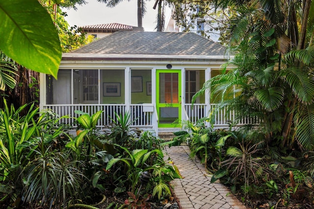 bungalow with a porch, roof with shingles, and a sunroom