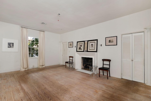 unfurnished room featuring a fireplace with flush hearth, visible vents, and light wood finished floors