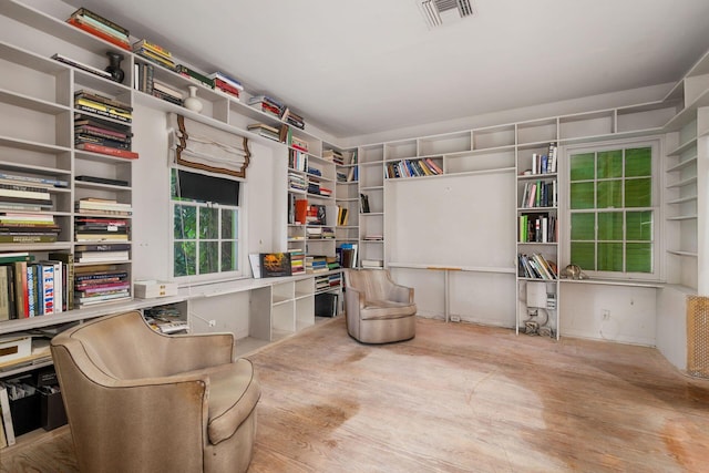 living area with wood finished floors, built in study area, and visible vents