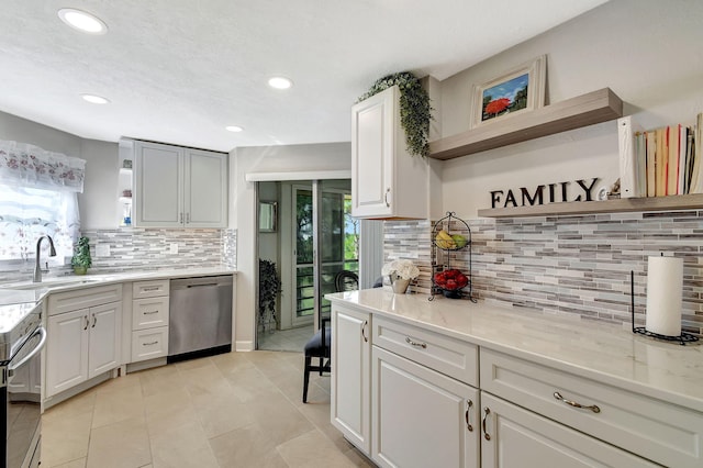 kitchen with sink, dishwasher, range, light stone counters, and white cabinets