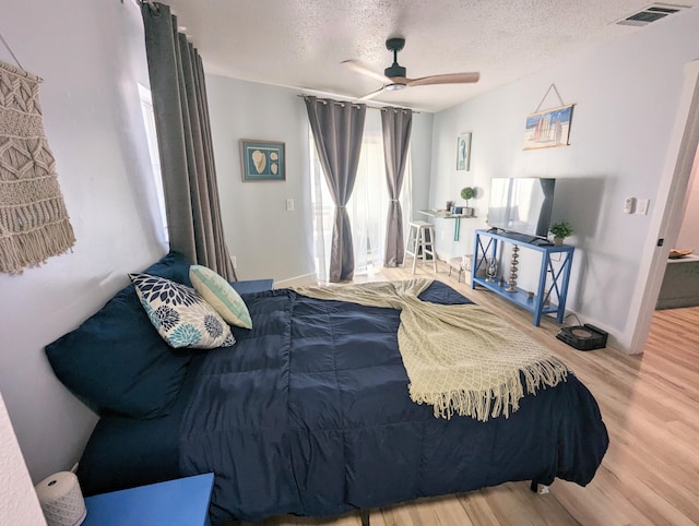 bedroom featuring ceiling fan, wood-type flooring, and a textured ceiling