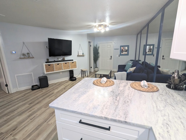 kitchen with light stone counters, white cabinets, and light hardwood / wood-style floors