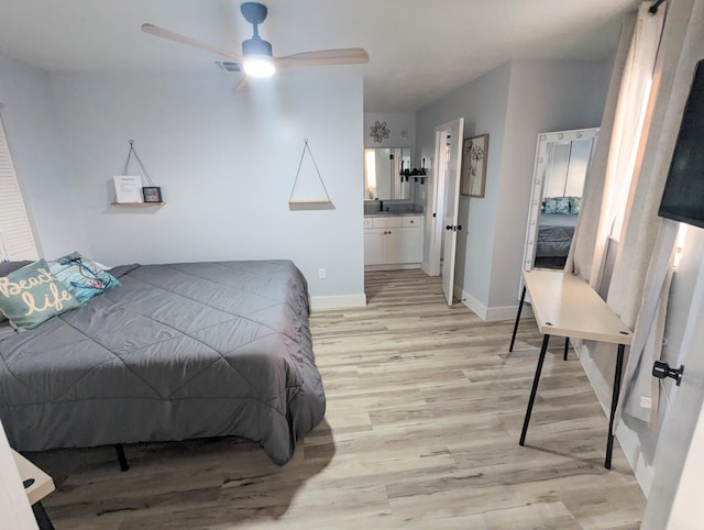 bedroom with ensuite bathroom, sink, and light wood-type flooring