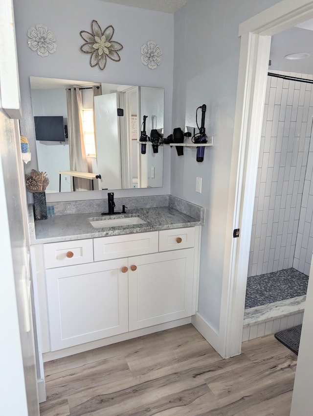 bathroom with vanity, tiled shower, and hardwood / wood-style floors