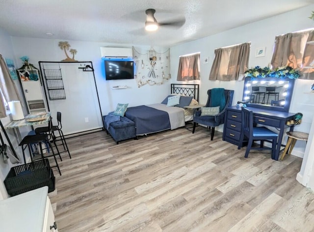 bedroom with ceiling fan, a wall mounted air conditioner, a textured ceiling, and light wood-type flooring