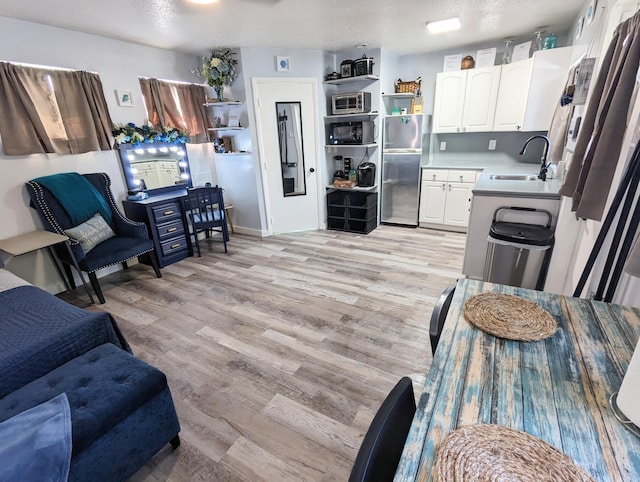 kitchen featuring appliances with stainless steel finishes, sink, light hardwood / wood-style flooring, and white cabinets