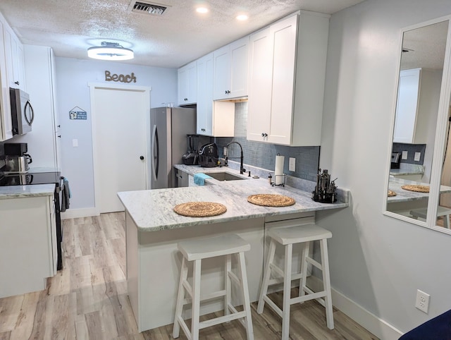 kitchen featuring white cabinetry, appliances with stainless steel finishes, sink, and kitchen peninsula