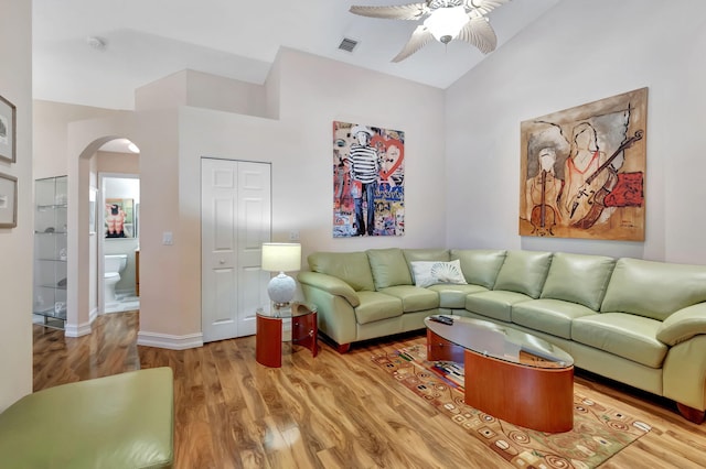 living room with visible vents, wood finished floors, arched walkways, ceiling fan, and vaulted ceiling