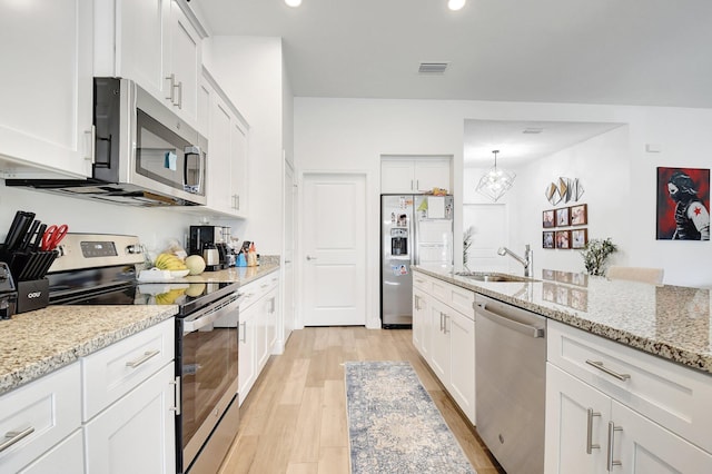 kitchen with sink, white cabinetry, stainless steel appliances, light stone countertops, and light hardwood / wood-style floors