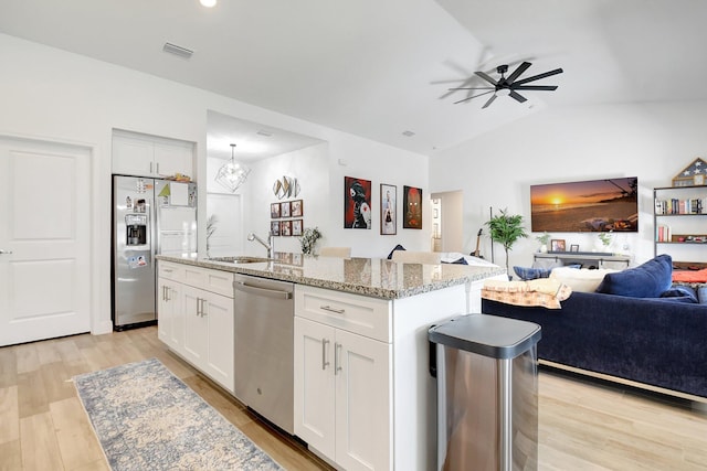 kitchen with appliances with stainless steel finishes, white cabinetry, light stone counters, a center island with sink, and light wood-type flooring