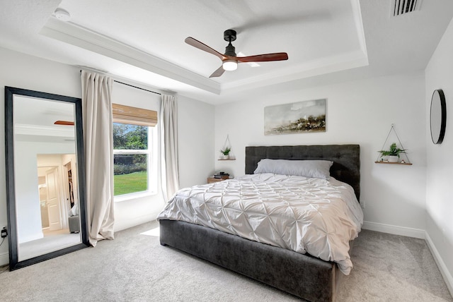 carpeted bedroom featuring crown molding, ceiling fan, and a tray ceiling