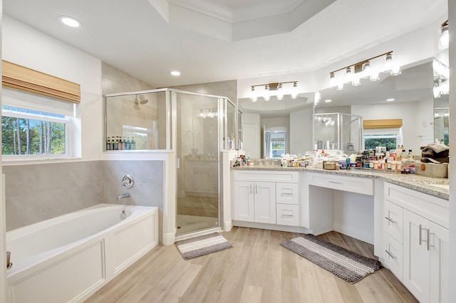 bathroom with hardwood / wood-style floors, vanity, independent shower and bath, and a wealth of natural light