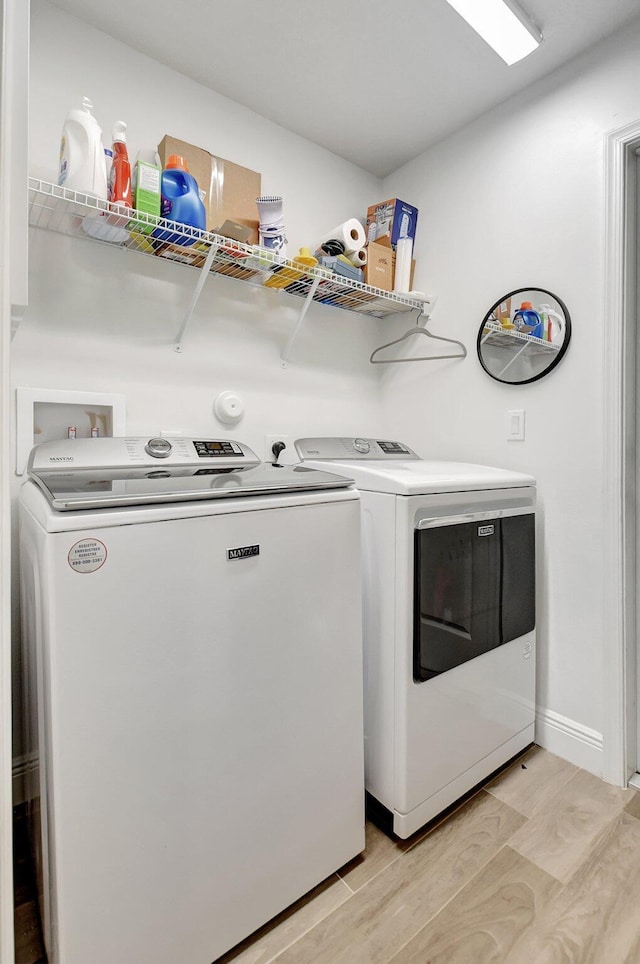 clothes washing area featuring washer and clothes dryer and light hardwood / wood-style floors