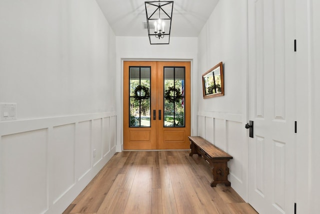 entryway featuring an inviting chandelier, light hardwood / wood-style flooring, and french doors