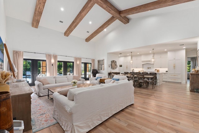 living room with beam ceiling, high vaulted ceiling, light wood-type flooring, and french doors