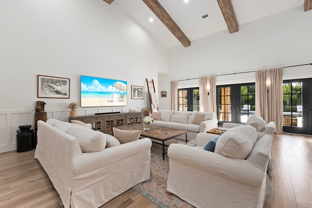 living room featuring light hardwood / wood-style flooring, high vaulted ceiling, a healthy amount of sunlight, french doors, and beamed ceiling