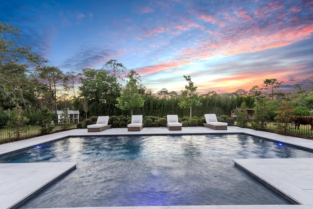 pool at dusk featuring a patio