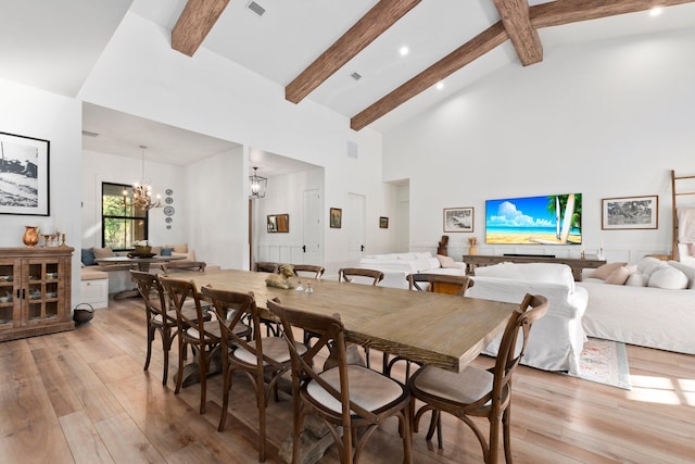 dining area featuring beamed ceiling, high vaulted ceiling, a chandelier, and light hardwood / wood-style flooring