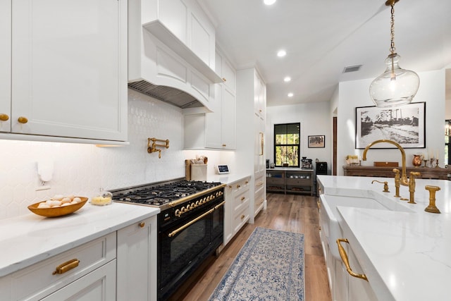 kitchen with pendant lighting, double oven range, light stone countertops, and white cabinets