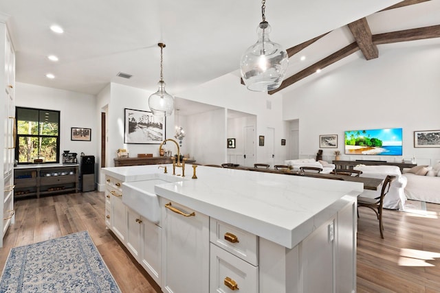 kitchen with white cabinetry, sink, decorative light fixtures, and an island with sink