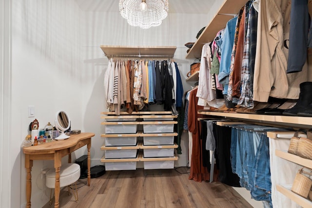 spacious closet featuring an inviting chandelier and hardwood / wood-style floors