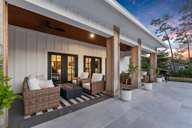 patio terrace at dusk featuring french doors, ceiling fan, and a fire pit