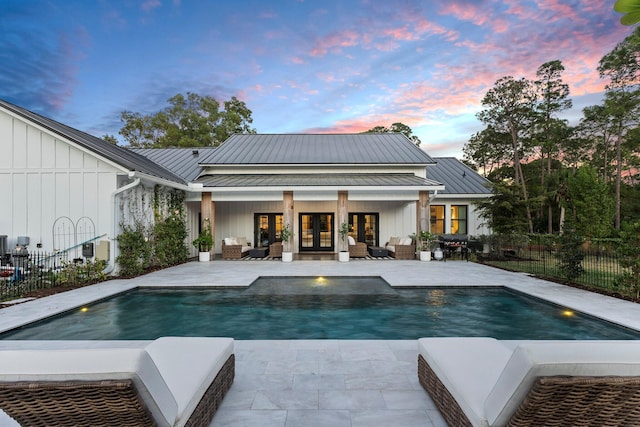 pool at dusk featuring a patio and french doors