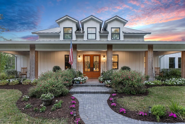 exterior entry at dusk featuring a porch and french doors