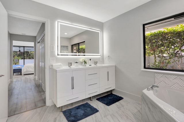 bathroom with vanity, tiled tub, and plenty of natural light