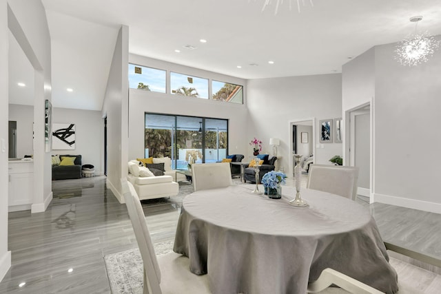 dining space with an inviting chandelier, light hardwood / wood-style flooring, and a high ceiling